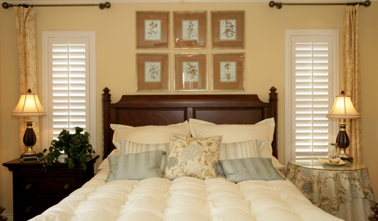 Tall plantation shutters framing bed in a bedroom in Fort Lauderdale 